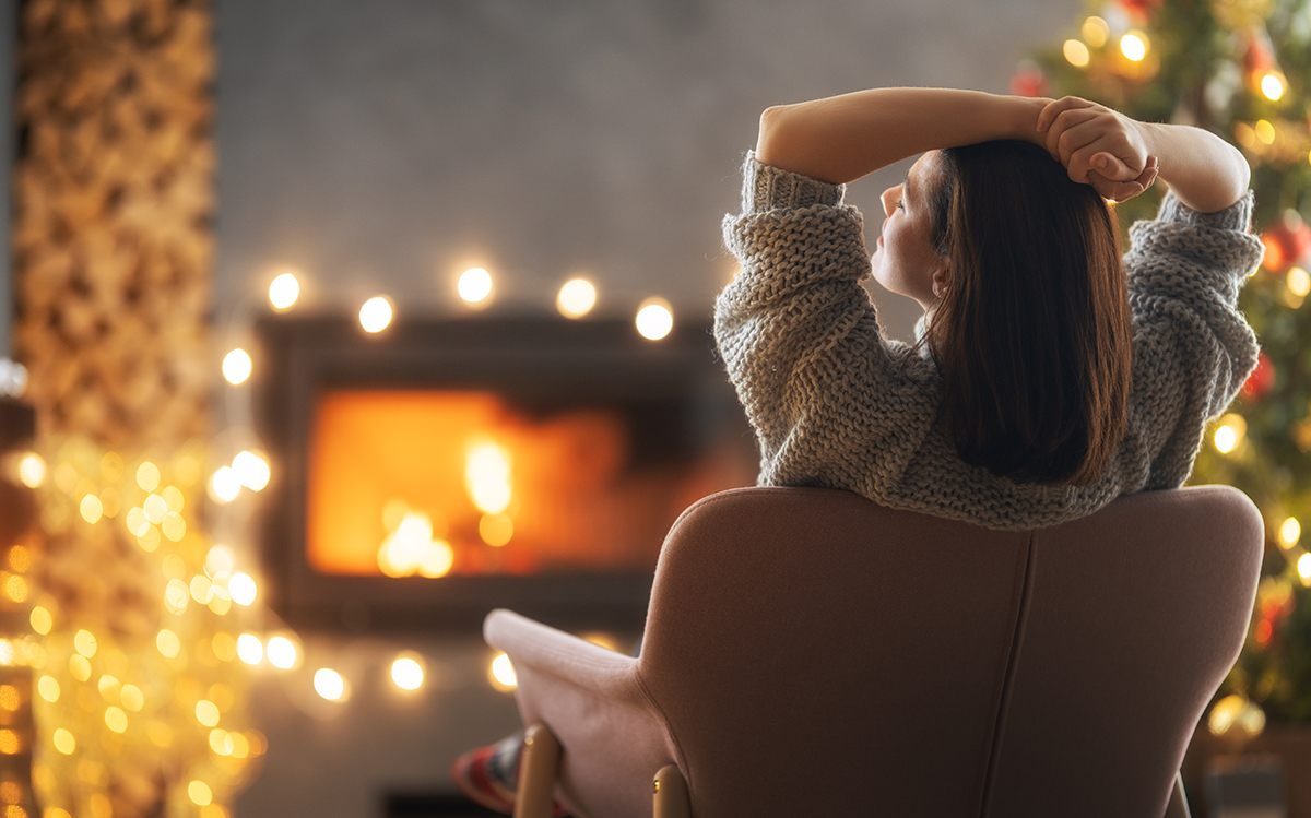 woman relaxing by fireplace with christmas tree